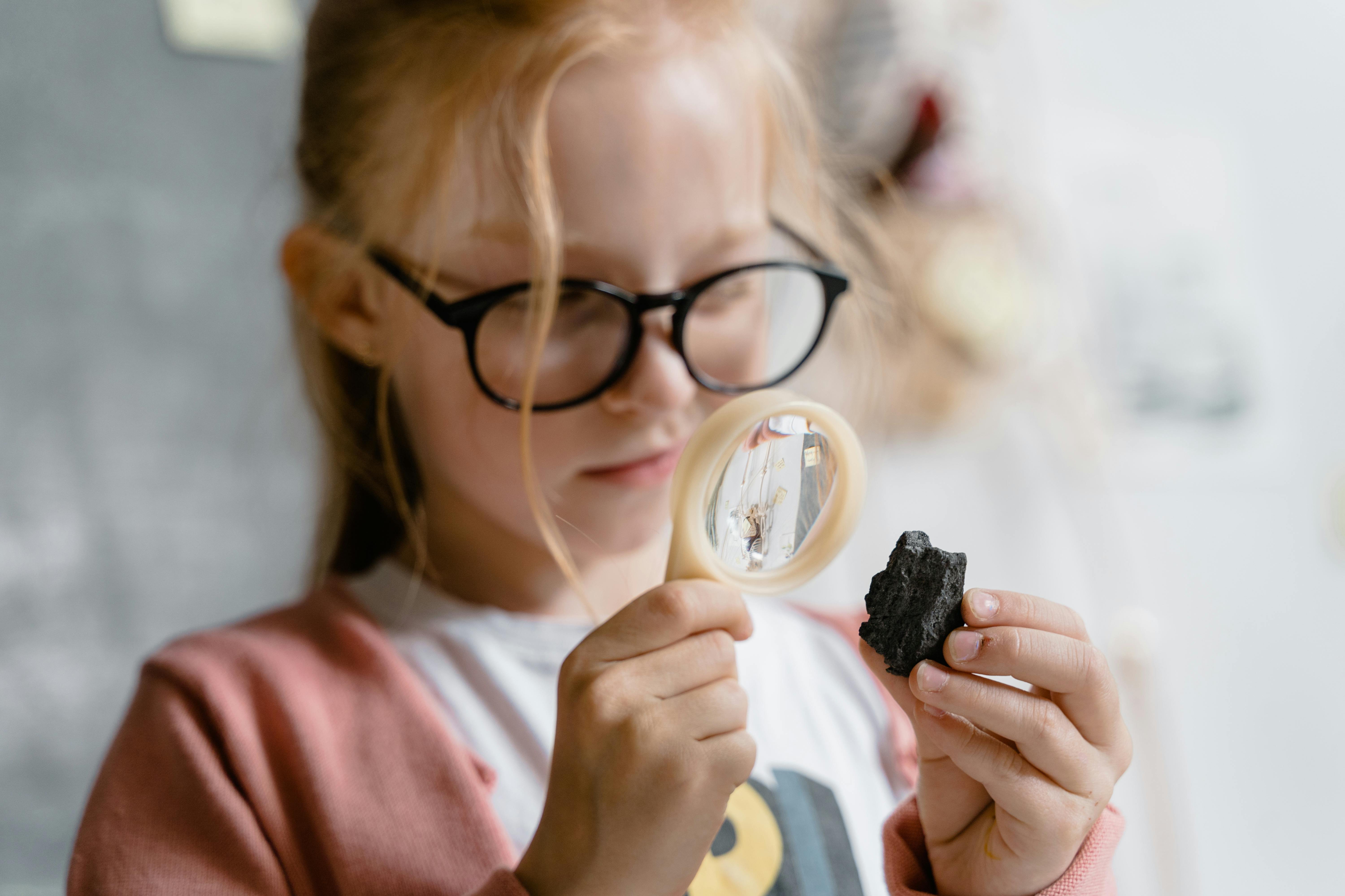 Girl with magnifying glass and rock