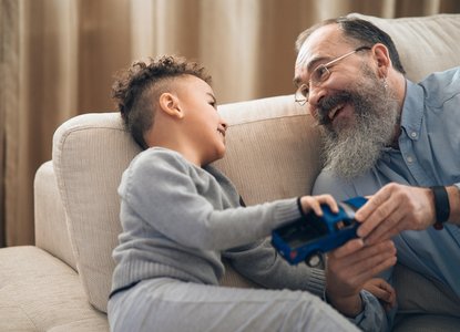 father/grandfather and boy laughing and holding a car